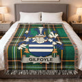 Tartan blanket with GILFOYLE crest displayed on a bed.