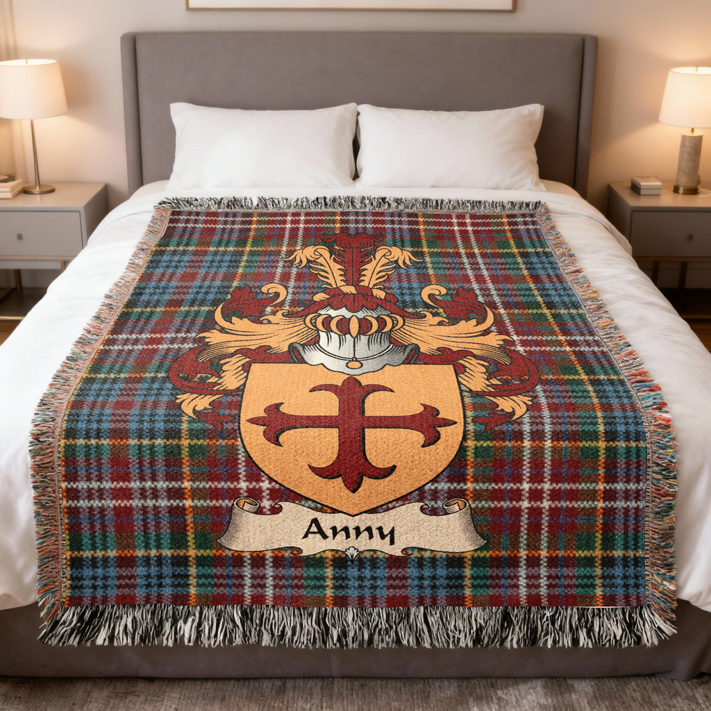 Anny Scottish family crest woven blanket on a Caledonia tartan background, displayed on a bed