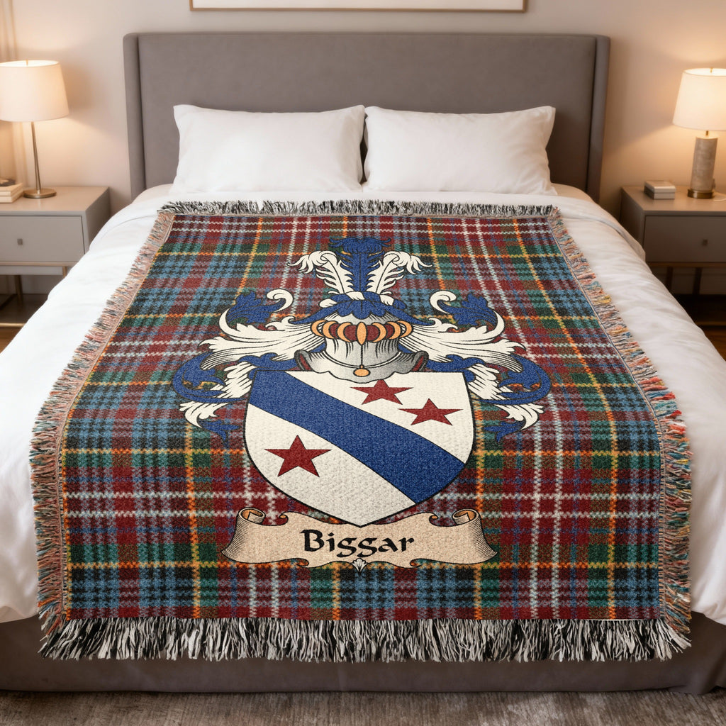 Biggar Scottish family crest woven blanket on a Caledonia tartan background, displayed on a bed