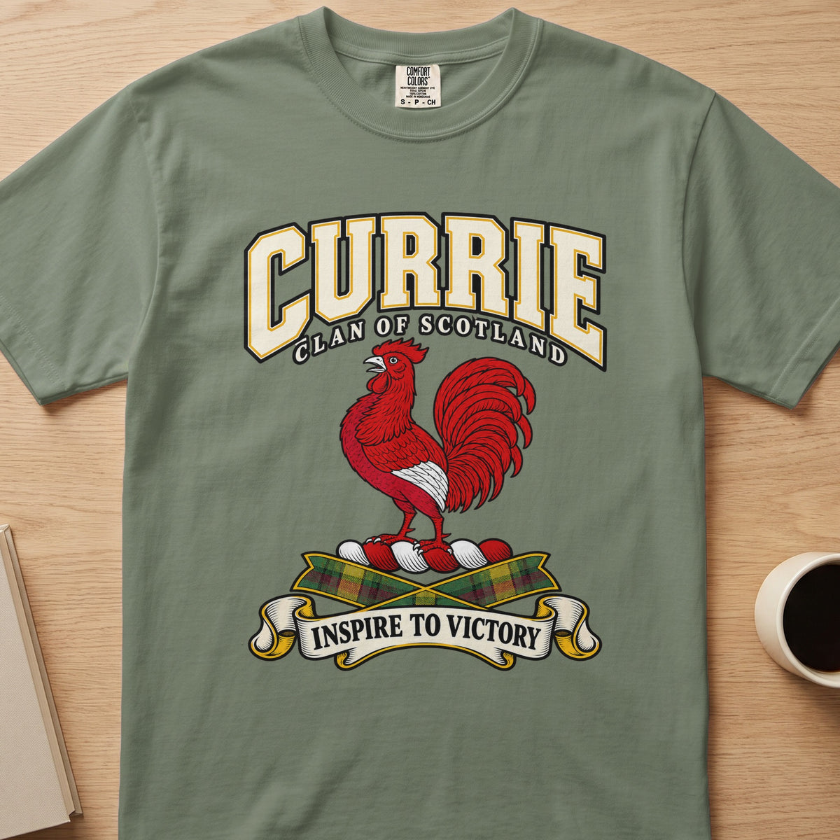 Currie clan crest with red rooster on a sage green Comfort Colors T-shirt, front view