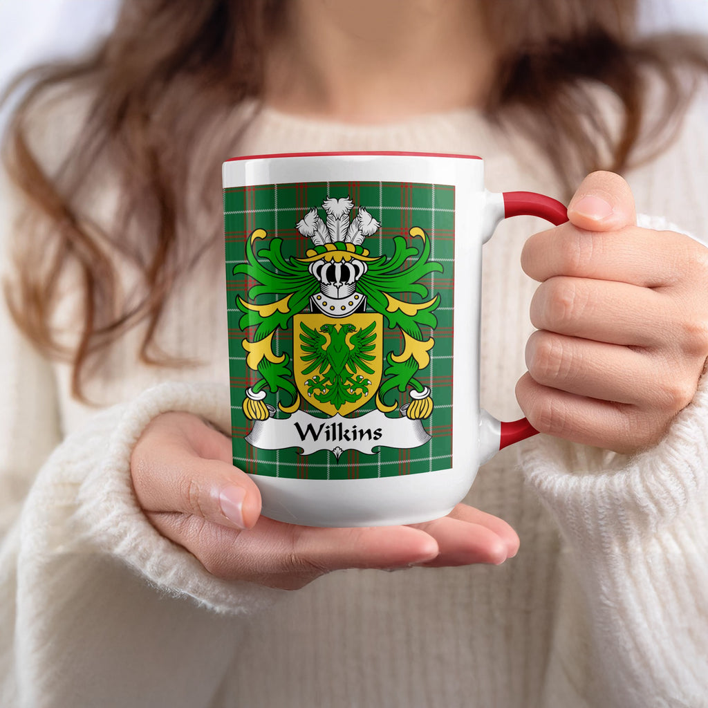 Mug with Wilkins family crest and green tartan pattern held by hands.