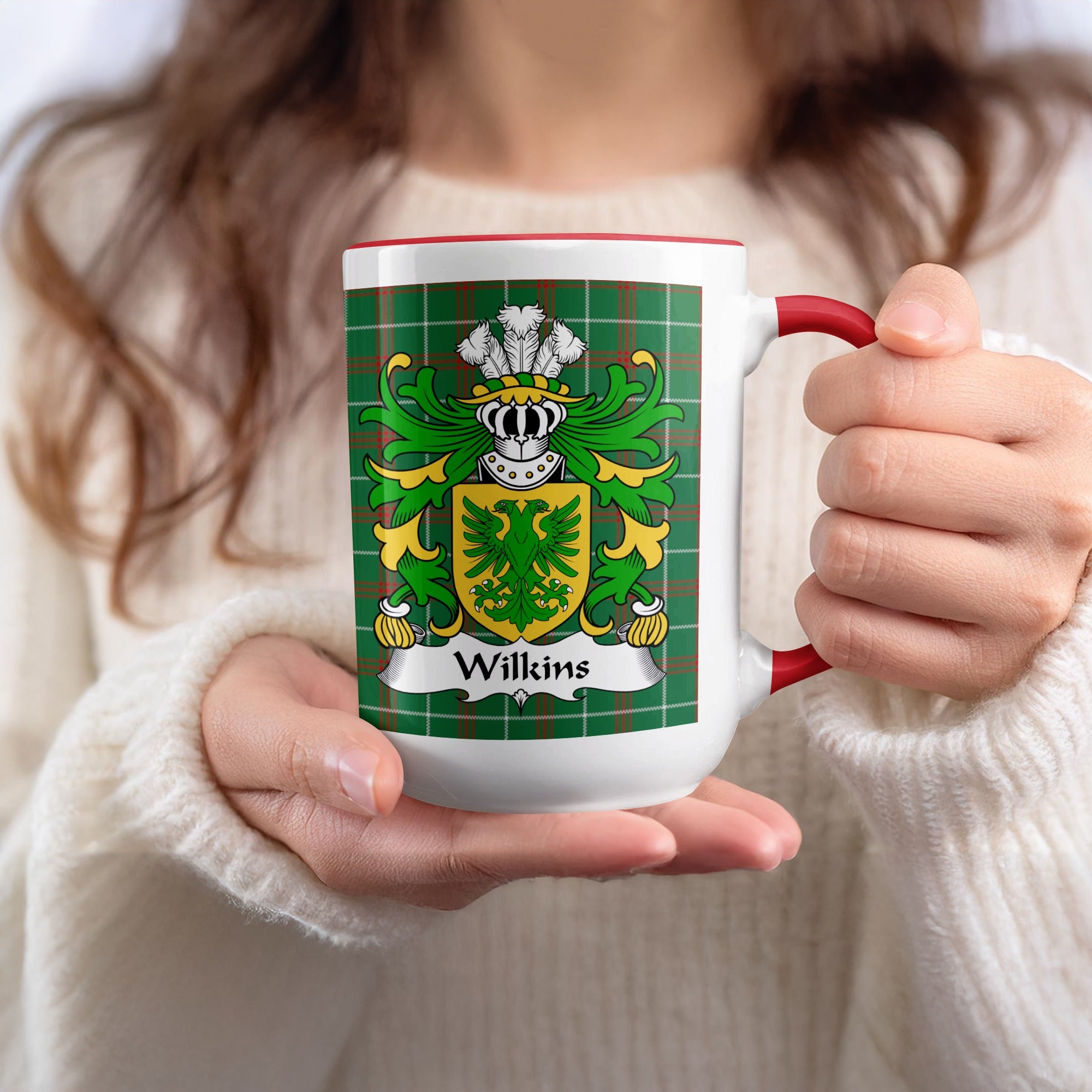 Mug with Wilkins family crest and green tartan pattern held by hands.