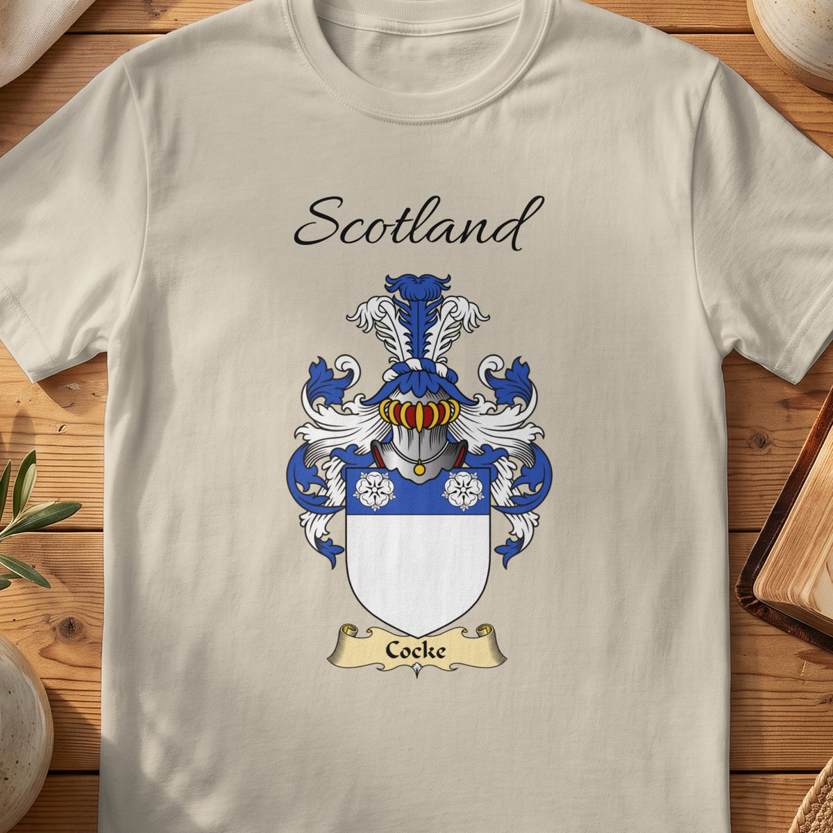 Sand Cocke Scottish family shield T-shirt featuring three white flowers on a blue band