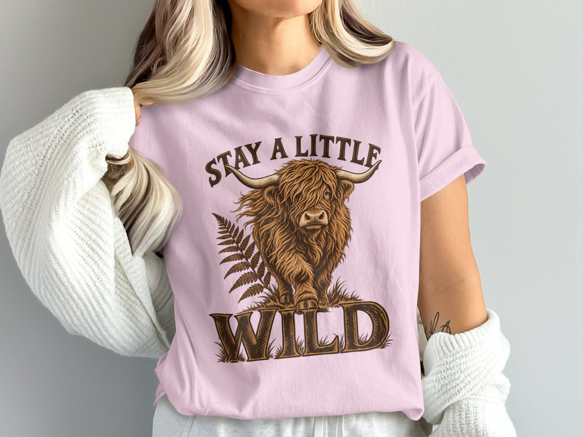 Model wearing the Stay a Little Wild Highland cow Comfort Colors T-shirt in Blossom