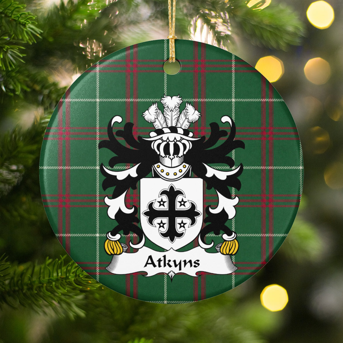 Atkyns ornament among Christmas tree branches and warm lights; a black decorative cross surrounded by four small black stars on white on Welsh national tartan.