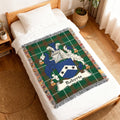 Tapestry blanket with Roberts family crest on a white bed.