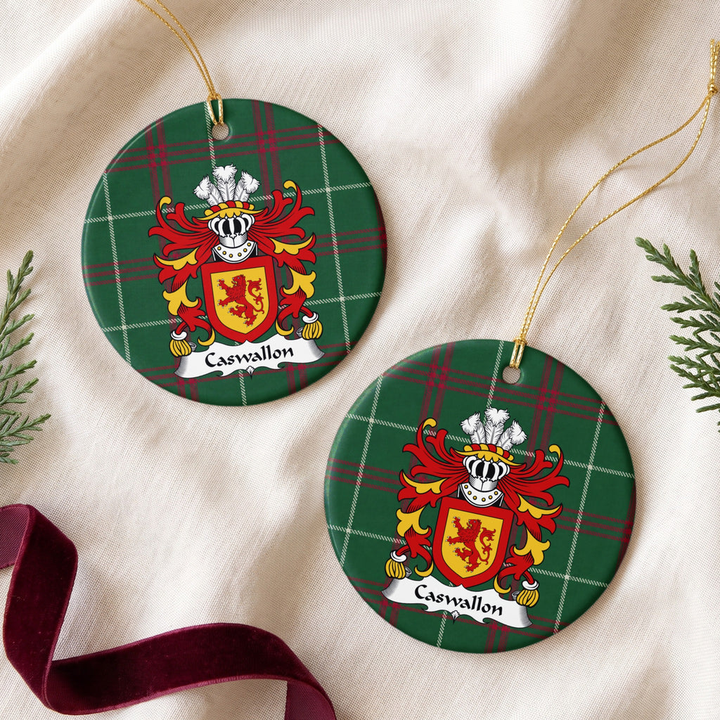 Two Caswallon ornaments on cream fabric beside evergreen sprigs and burgundy ribbon; a red upright lion on a gold shield with a red border on Welsh national tartan.