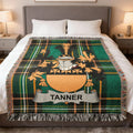 Tanner family crest on green plaid throw blanket draped on a bed.