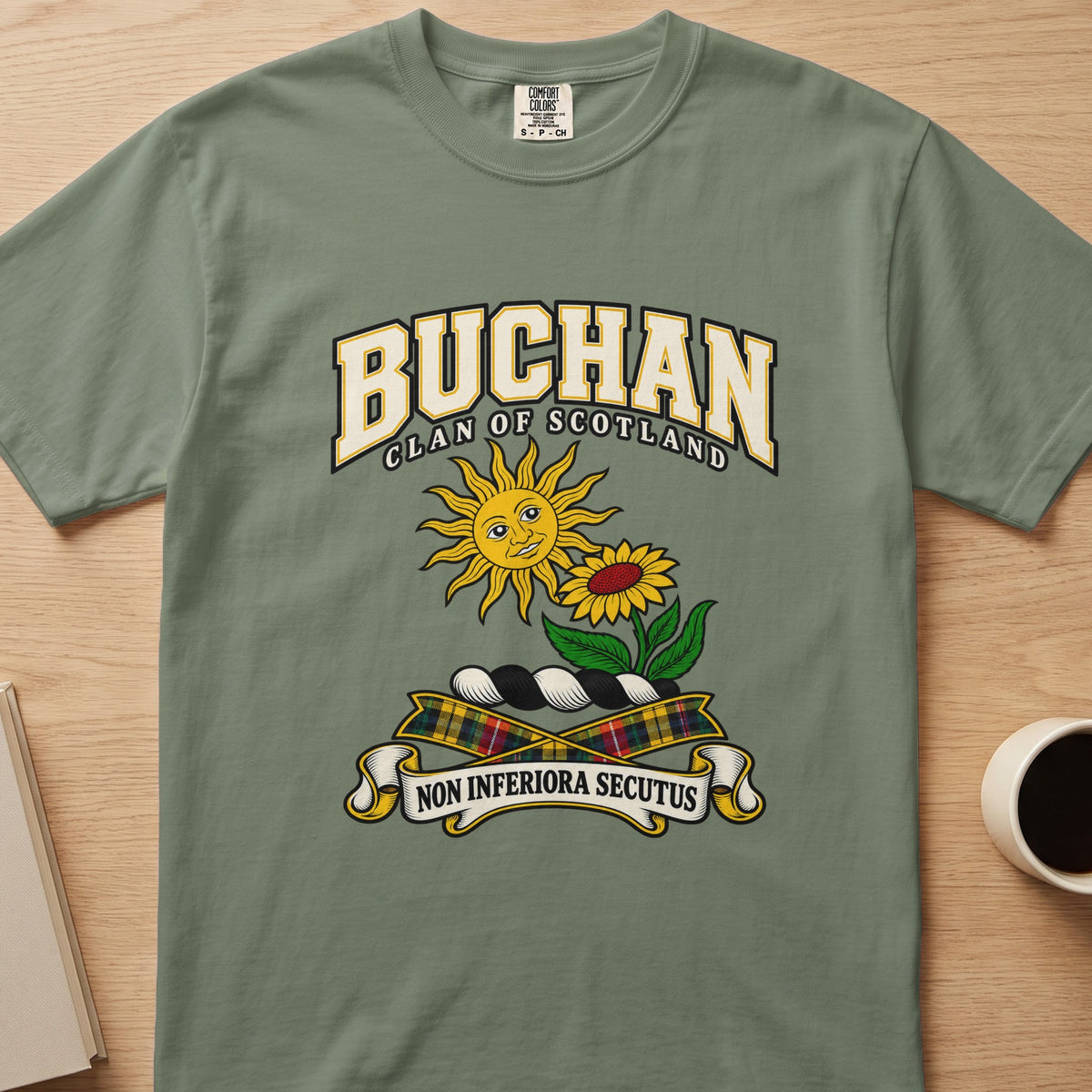 Buchan clan crest with sun and flower on a sage green Comfort Colors T-shirt, front view
