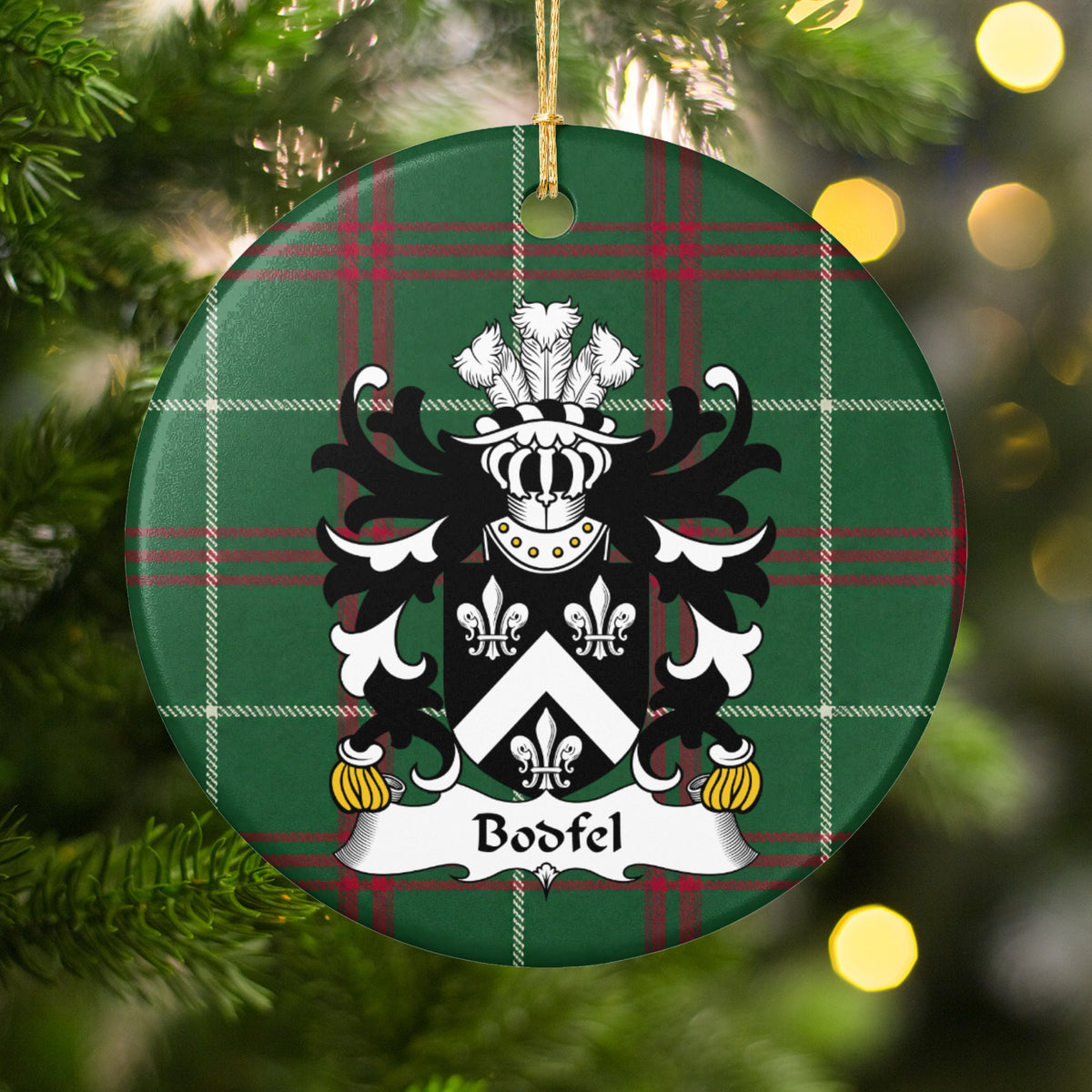 Bodfel ornament hanging in a Christmas tree with warm lights; a white chevron between three white fleurs-de-lis on black on Welsh national tartan.