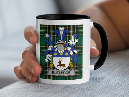 White mug with black handle featuring Rutledge family crest on plaid background.