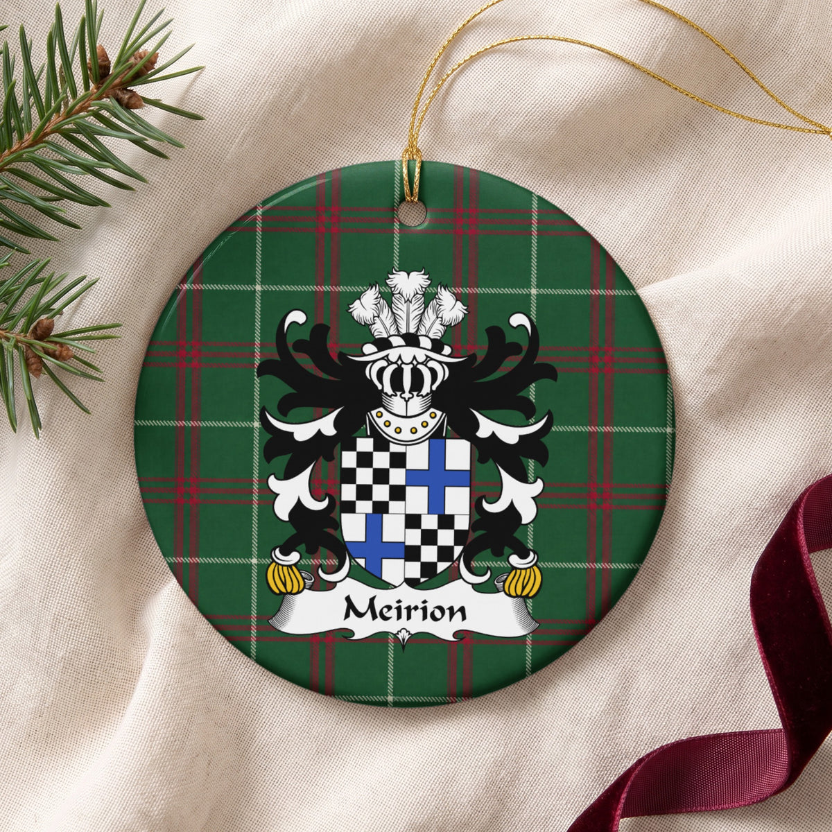 Meirion ornament on cream fabric with gold string, evergreen and burgundy ribbon; a quartered shield with black-and-white checks and blue crosses on Welsh National Tartan.