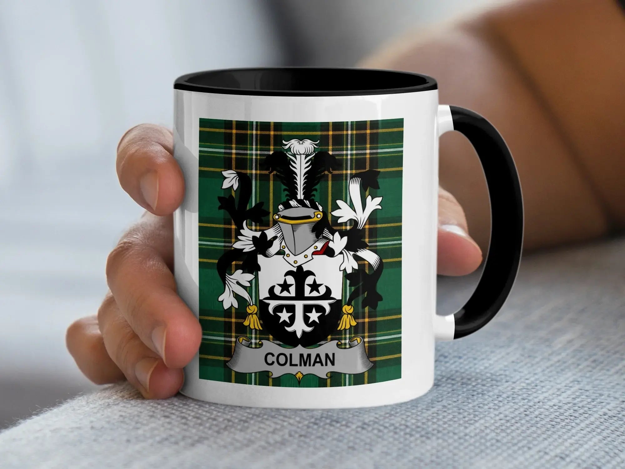 White mug with black rim featuring Colman family crest on green plaid background.