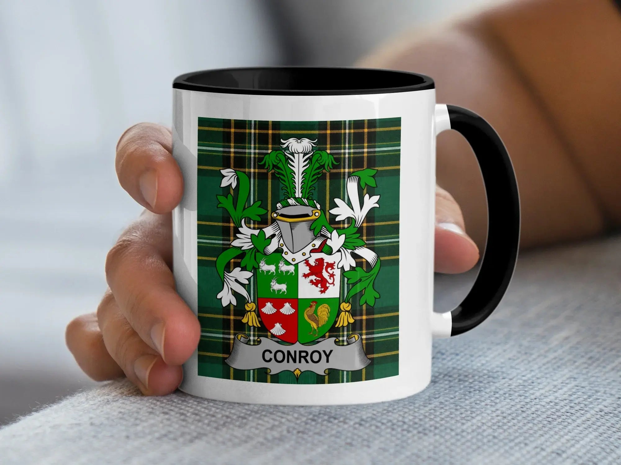 White mug with black rim displaying Conroy family crest on green plaid.