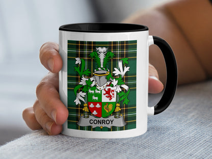 White mug with black rim displaying Conroy family crest on green plaid.