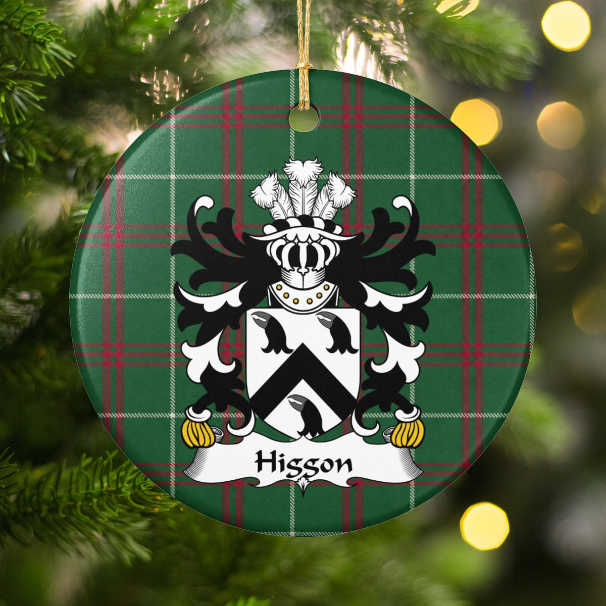Higgon ornament hanging in a Christmas tree with warm lights; three black bird heads and a black chevron on a white shield on Welsh national tartan.