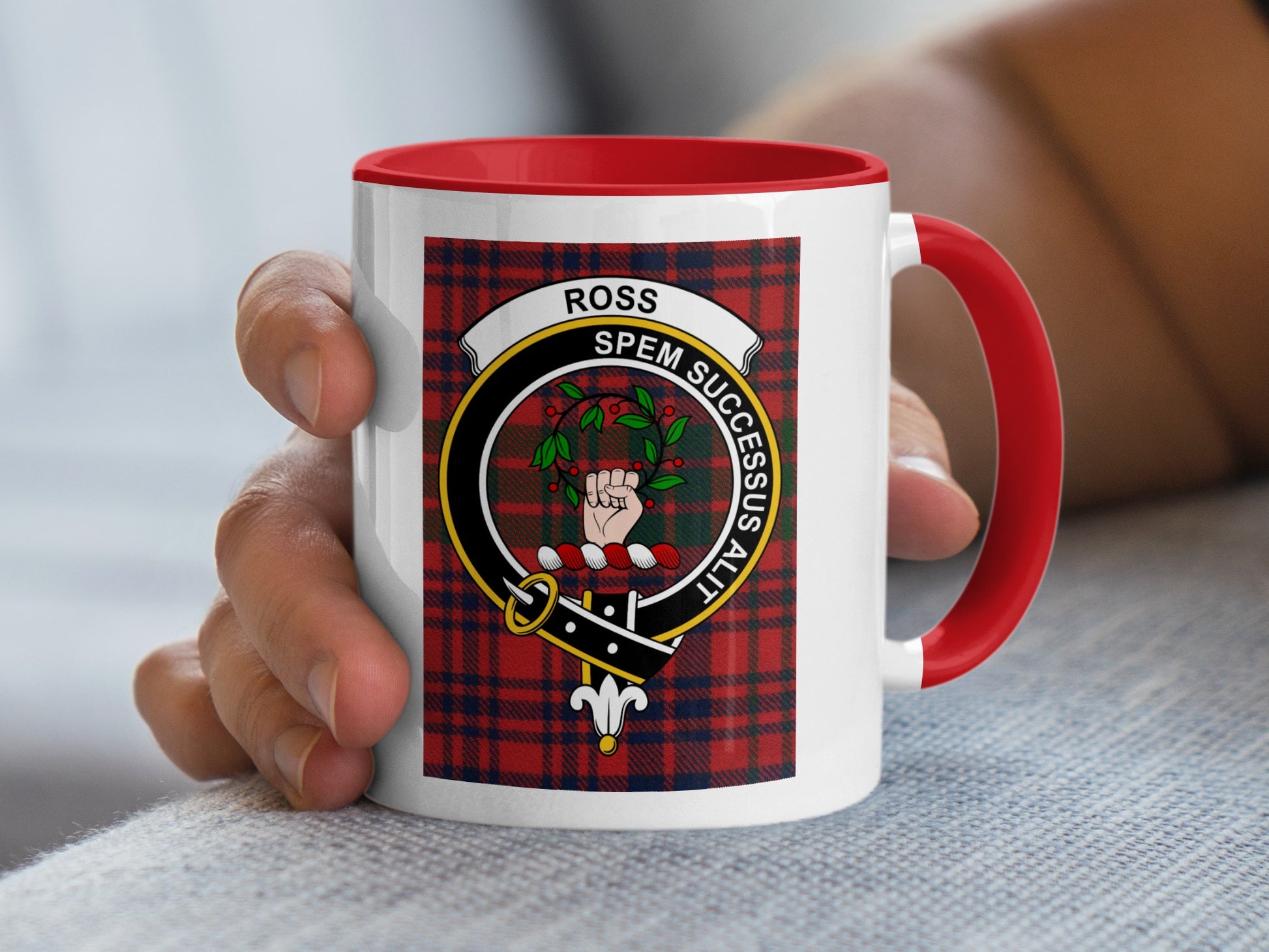 Red-handled mug with Ross tartan and crest, held by a hand.