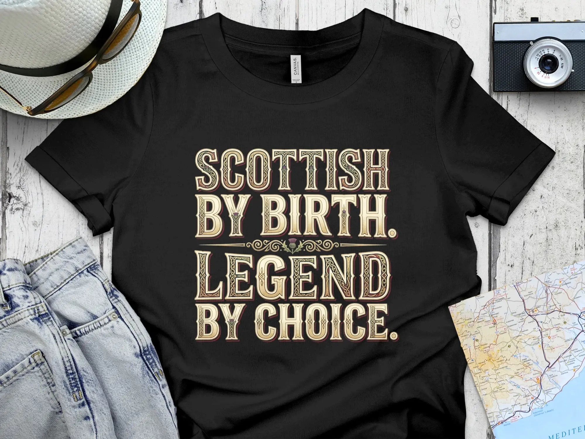 Black t-shirt with "Scottish by Birth, Legend by Choice" text in ornate gold font.