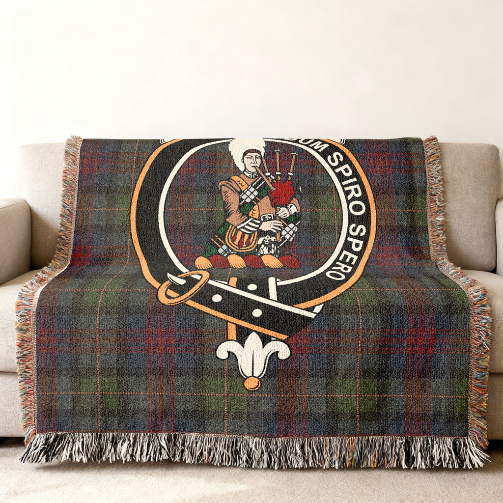 Close view of the MacLennan woven blanket draped over a sofa, showing the crest and fringed edges