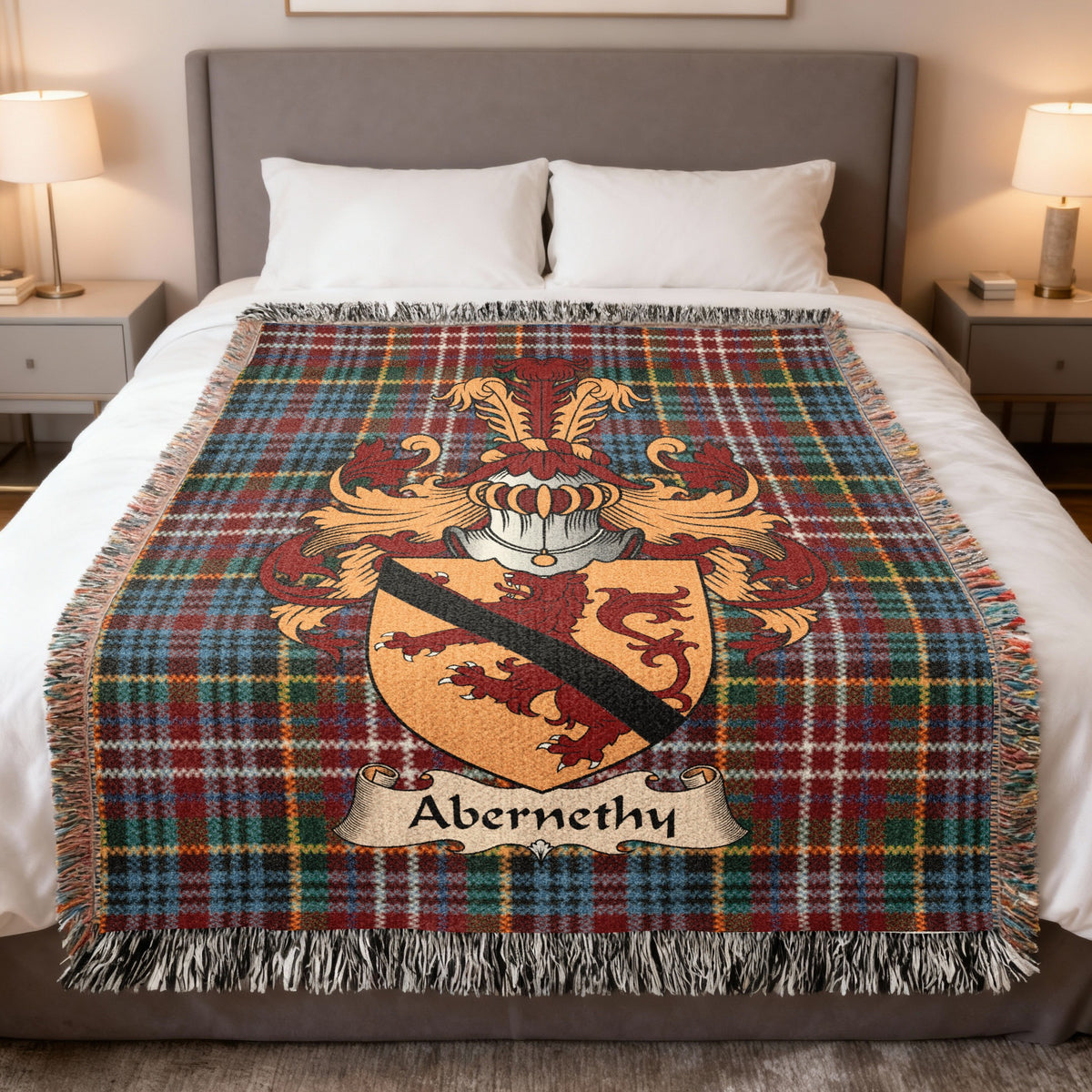 Abernethy Scottish family crest woven blanket on a Caledonia tartan background, displayed on a bed