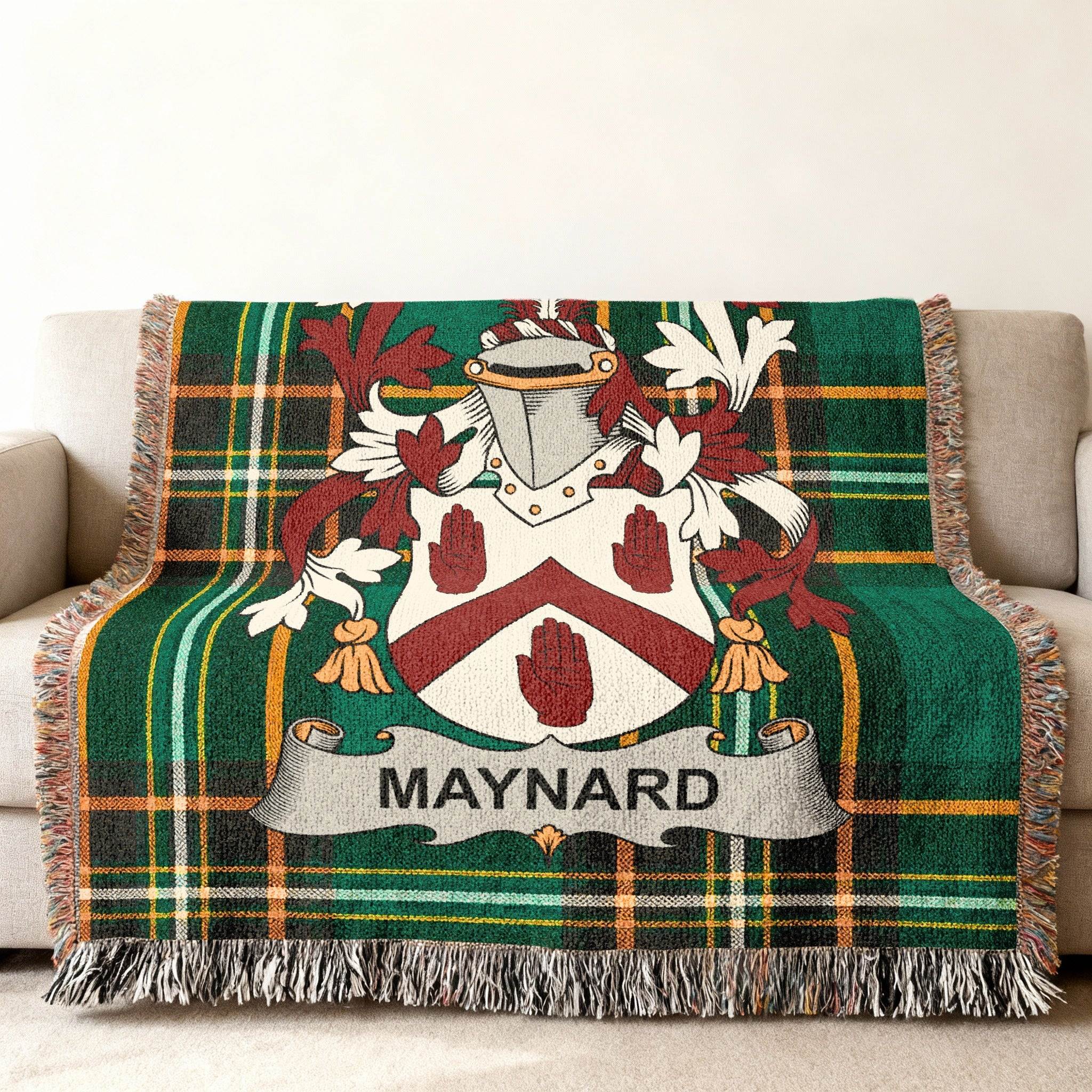 Green tartan blanket with Maynard family crest displayed on sofa.