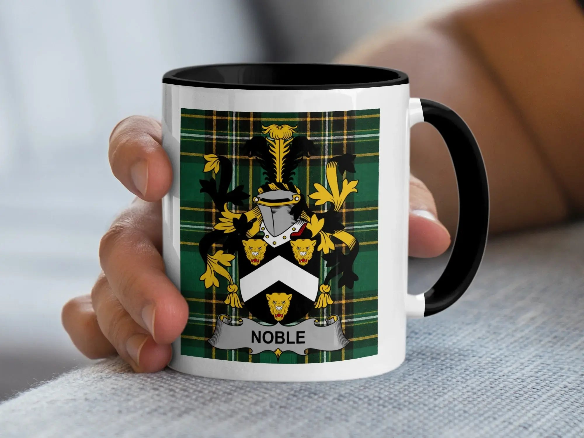 Mug with a coat of arms and "Noble" text held by a hand.
