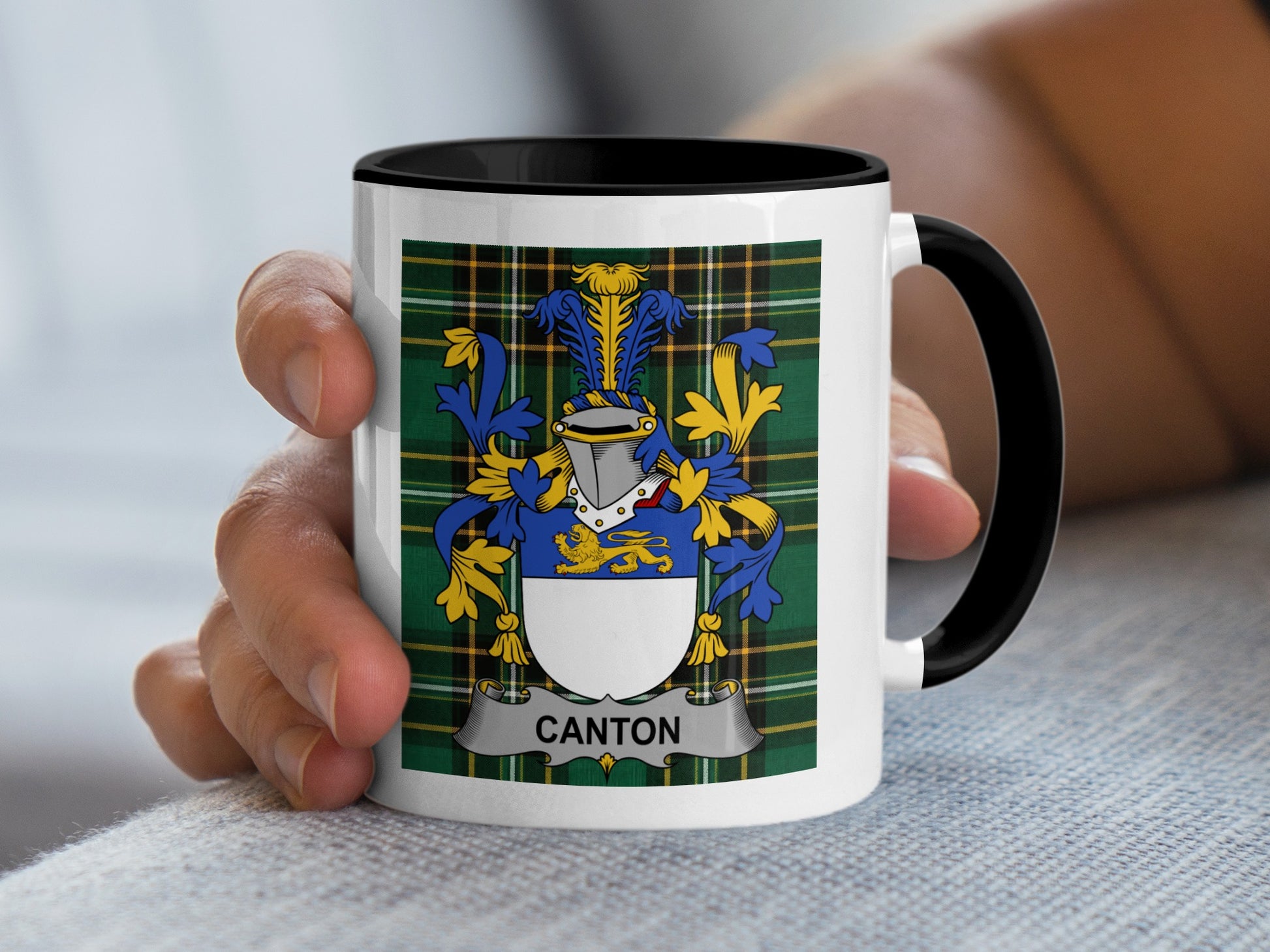 White mug with black rim and handle, displaying the Canton family crest on plaid.
