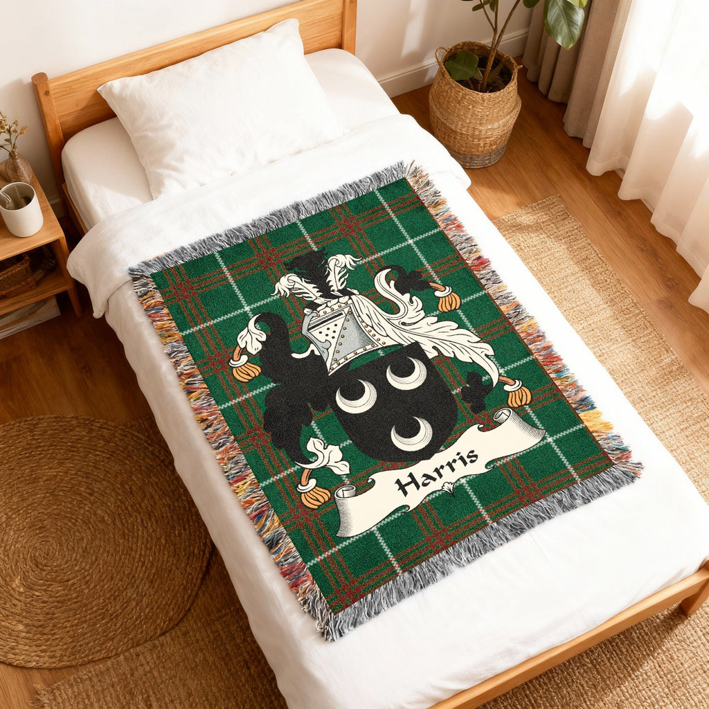 Green tartan woven blanket with Harris family crest on a bed.