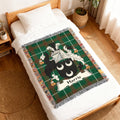 Green tartan woven blanket with Harris family crest on a bed.