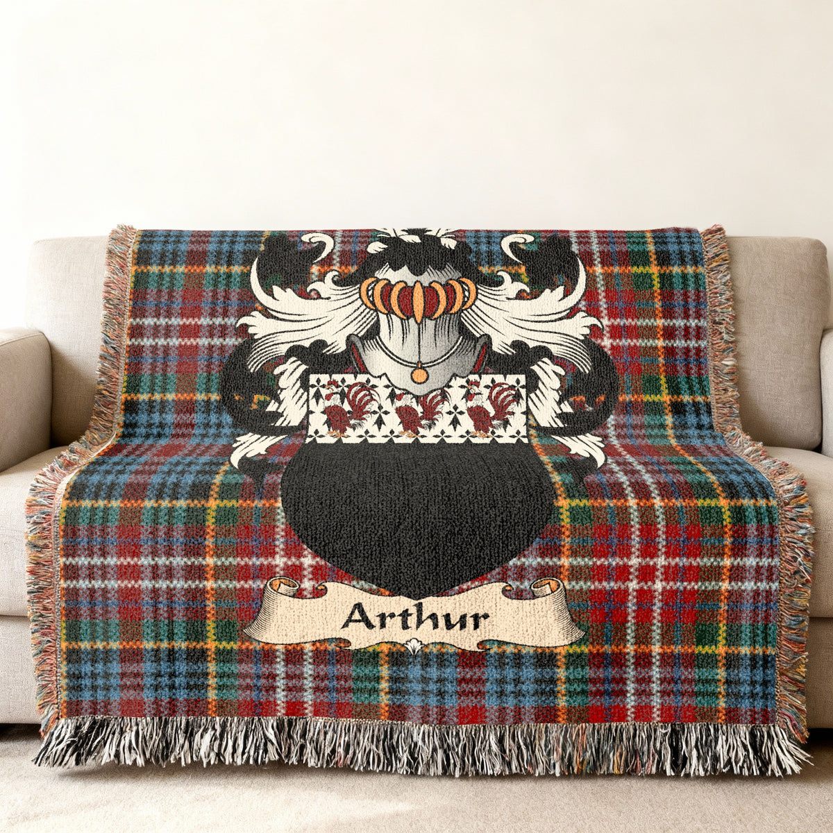 Arthur Scottish family shield woven blanket with Caledonia tartan background on a sofa