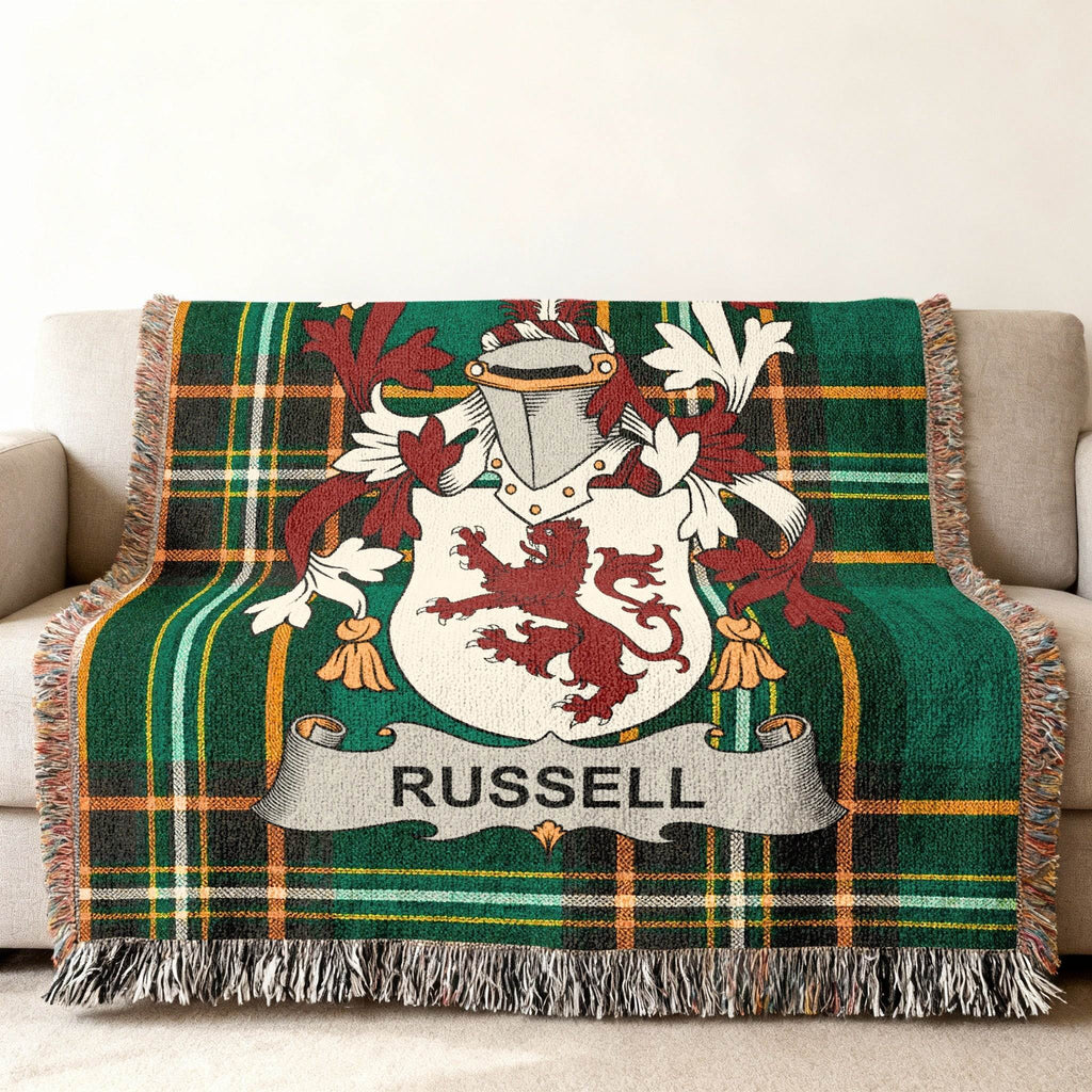 Green tartan throw blanket with Russell family crest displayed on a couch.