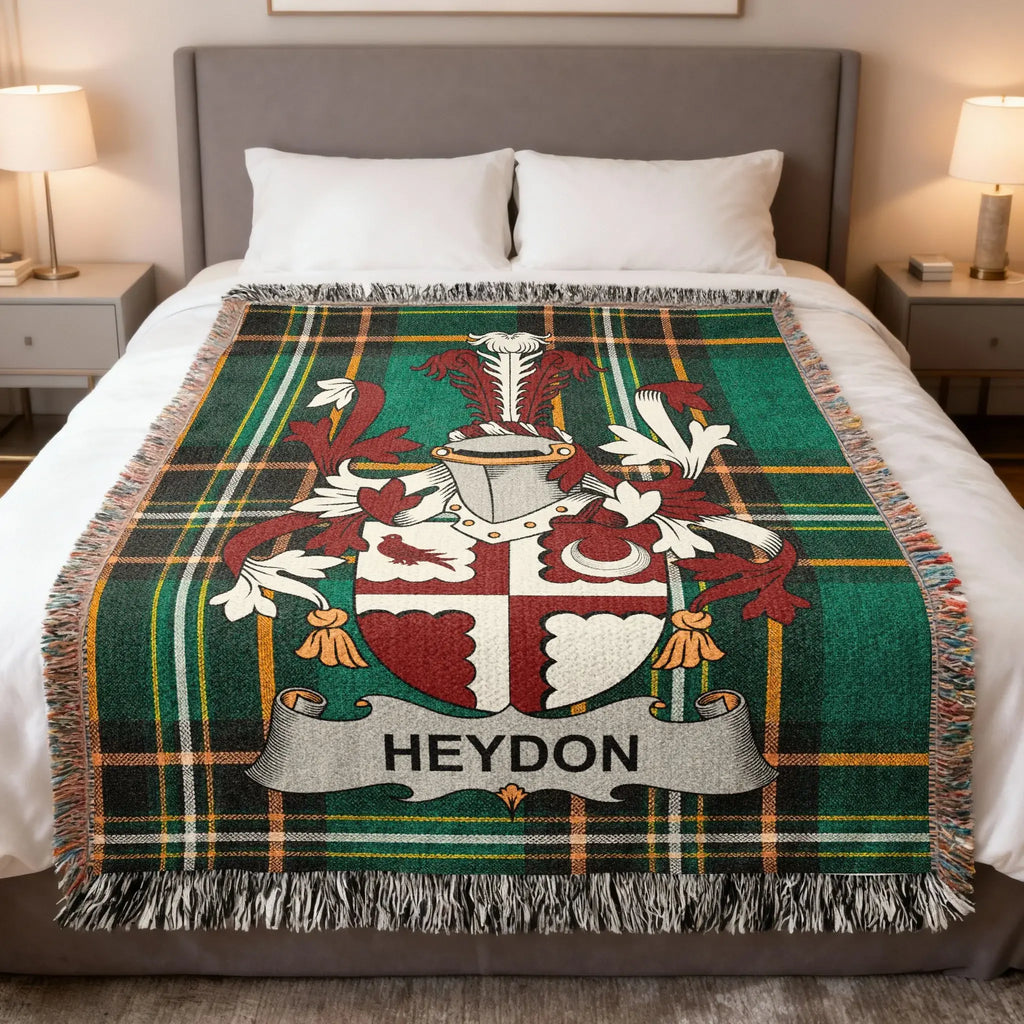 Tartan throw blanket with Heydon family crest on a bed.