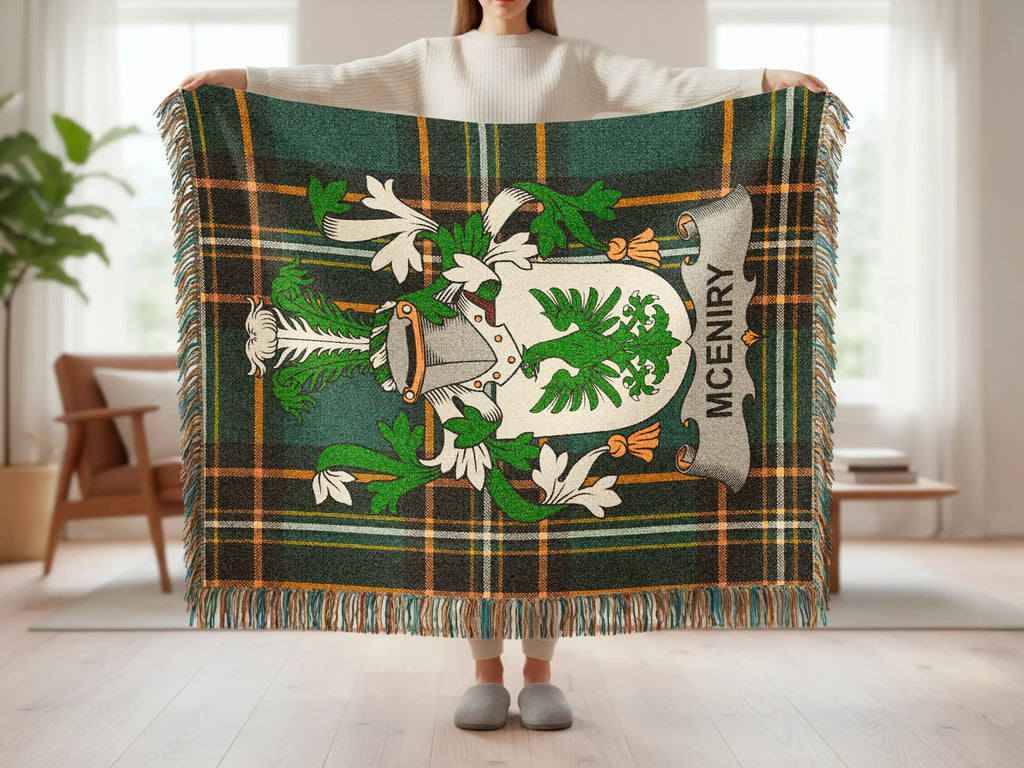 Tartan throw with MCENIRY crest and fringe, held by a person.