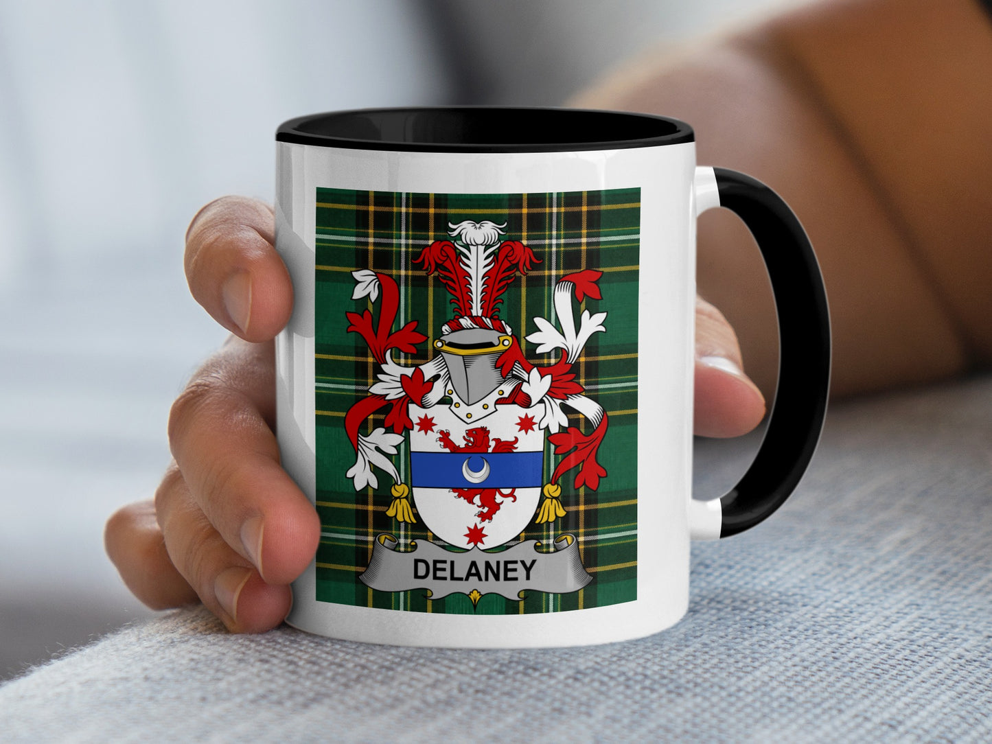 White mug with black handle featuring Delaney family crest on green plaid.