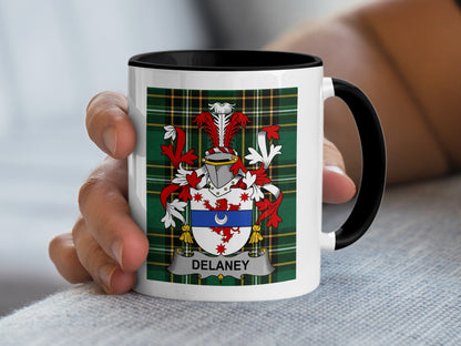 White mug with black handle featuring Delaney family crest on green plaid.