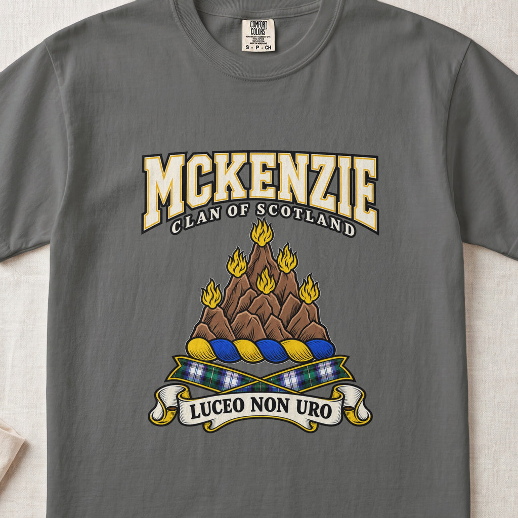 McKenzie graphic T-shirt in Pepper gray, front flat lay showing varsity lettering and brown rocky mountain-like mound with yellow flames.