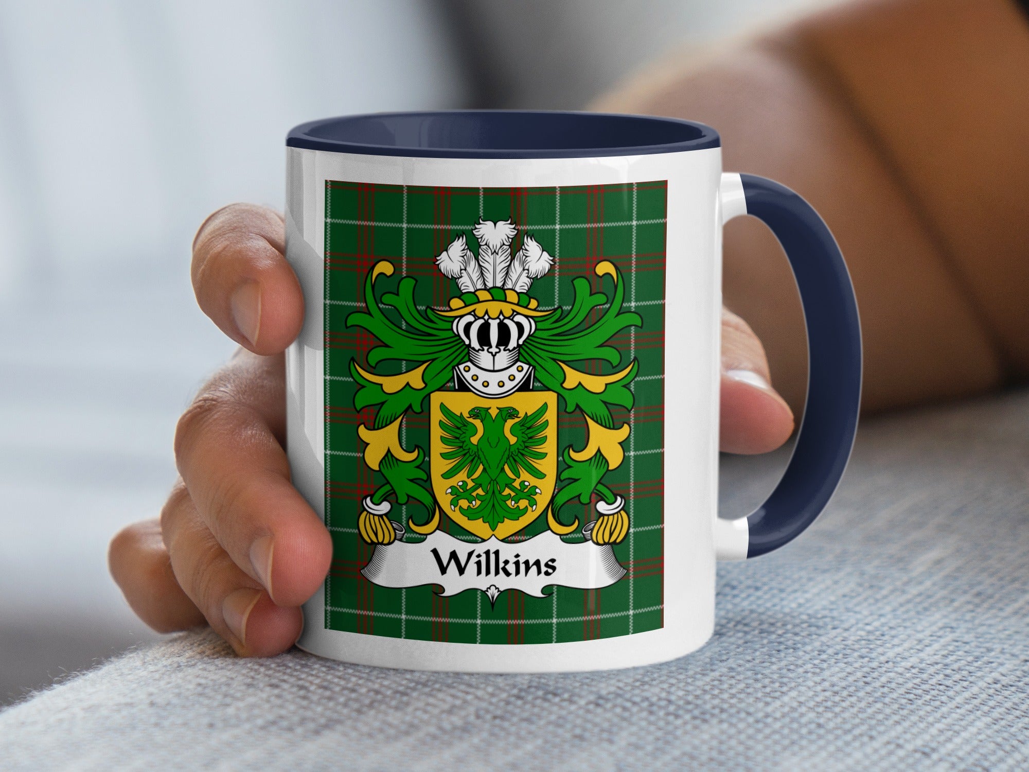 White mug with navy handle displaying Wilkins family crest on green tartan background.