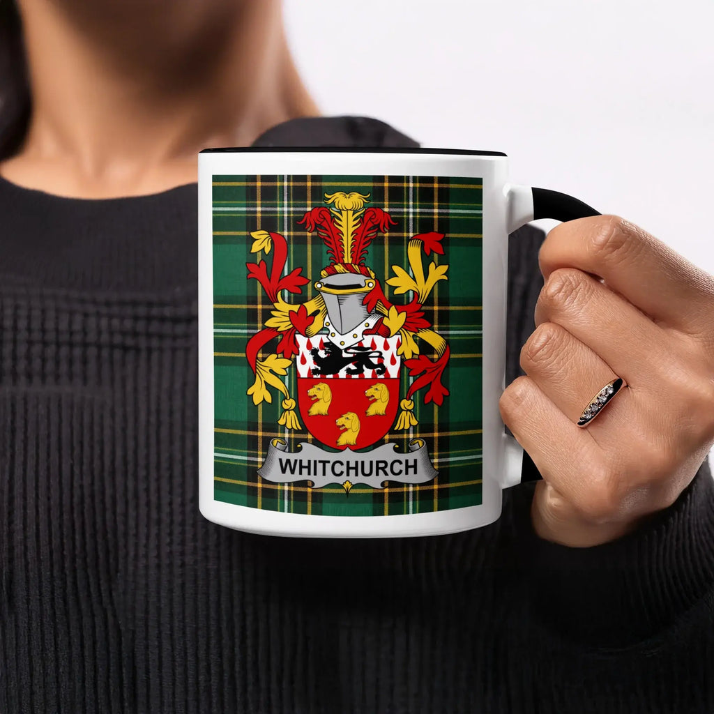 White mug with black trim featuring Whitchurch family crest on plaid background.