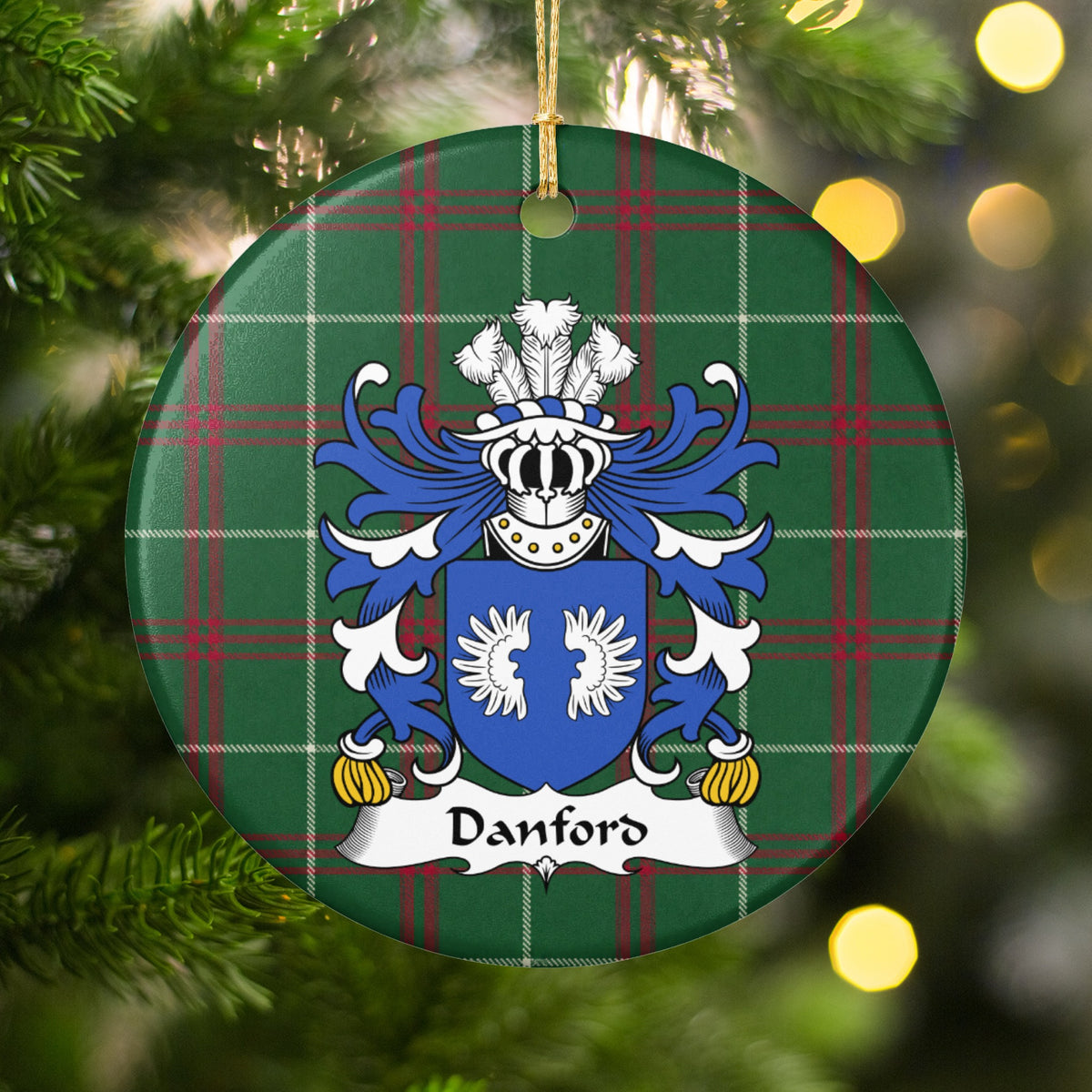 Danford ornament hanging among Christmas tree branches and warm lights; two white wings on a blue shield on Welsh national tartan.