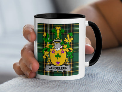 White mug with black rim displaying the Vandeleur family crest on a tartan background.