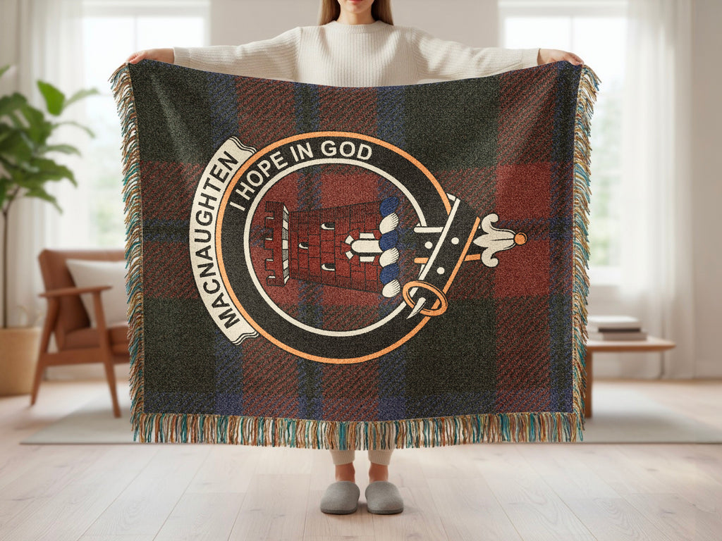 Person holding the MacNaughten woven blanket to show the full design, tartan background and fringe