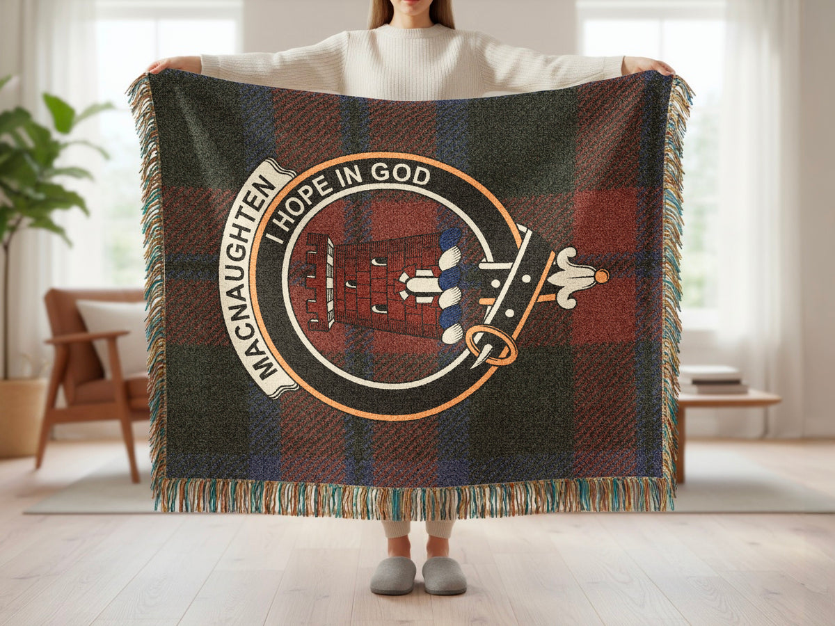 Person holding the MacNaughten woven blanket to show the full design, tartan background and fringe