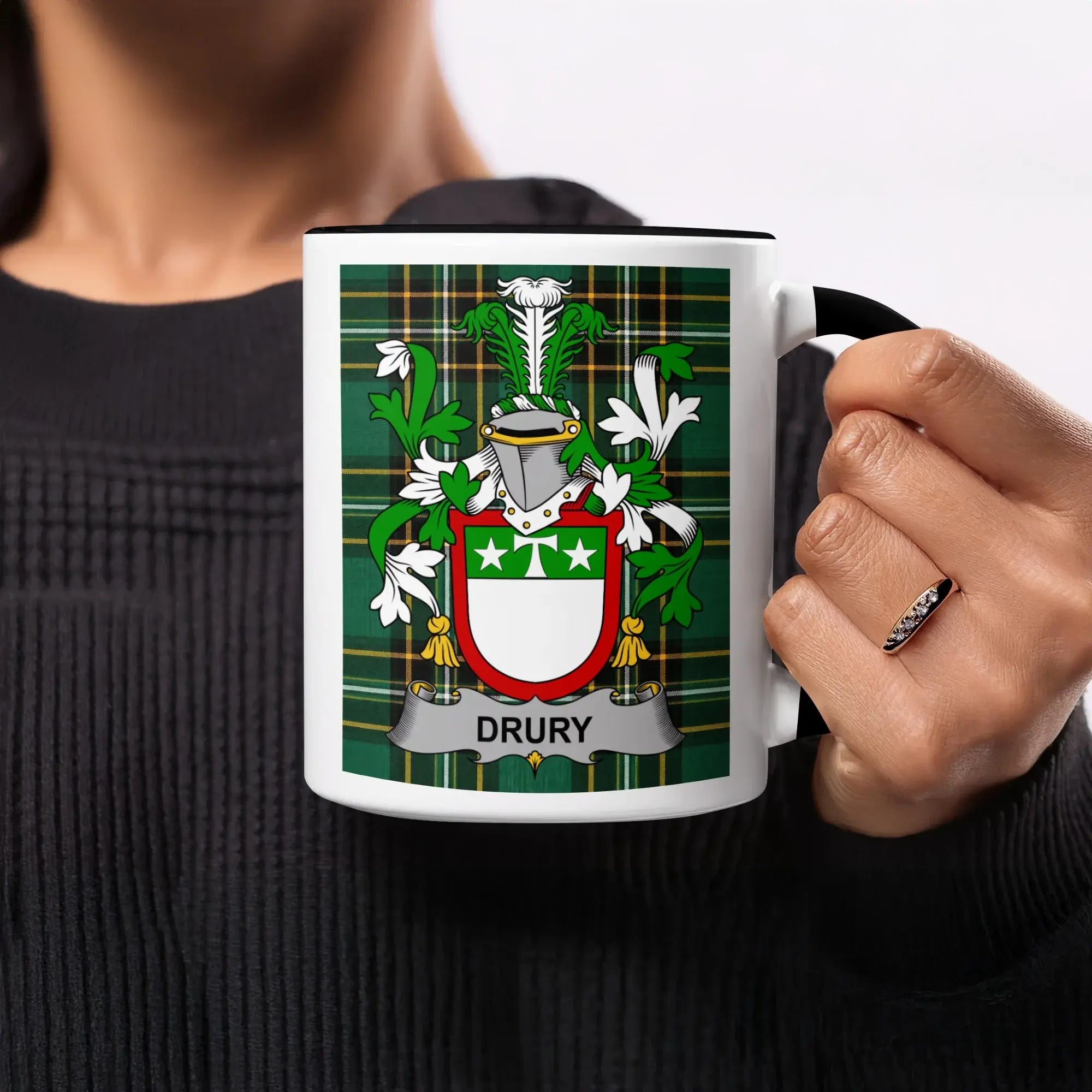 Drury family crest on a white mug held by a person.