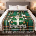 Wettenhall family crest on a green plaid throw blanket draped on a bed.