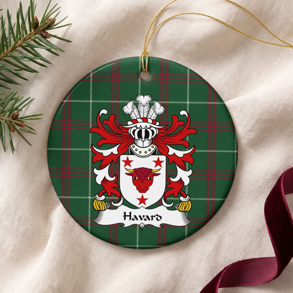 Havard ornament on cream fabric beside evergreen and burgundy ribbon, with gold string; a red bull head with gold horns and three red stars on a white shield.