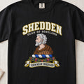 Shedden Scottish clan T-shirt in Black, front view with a gray-haired, bearded figure in a brown robe and motto design.