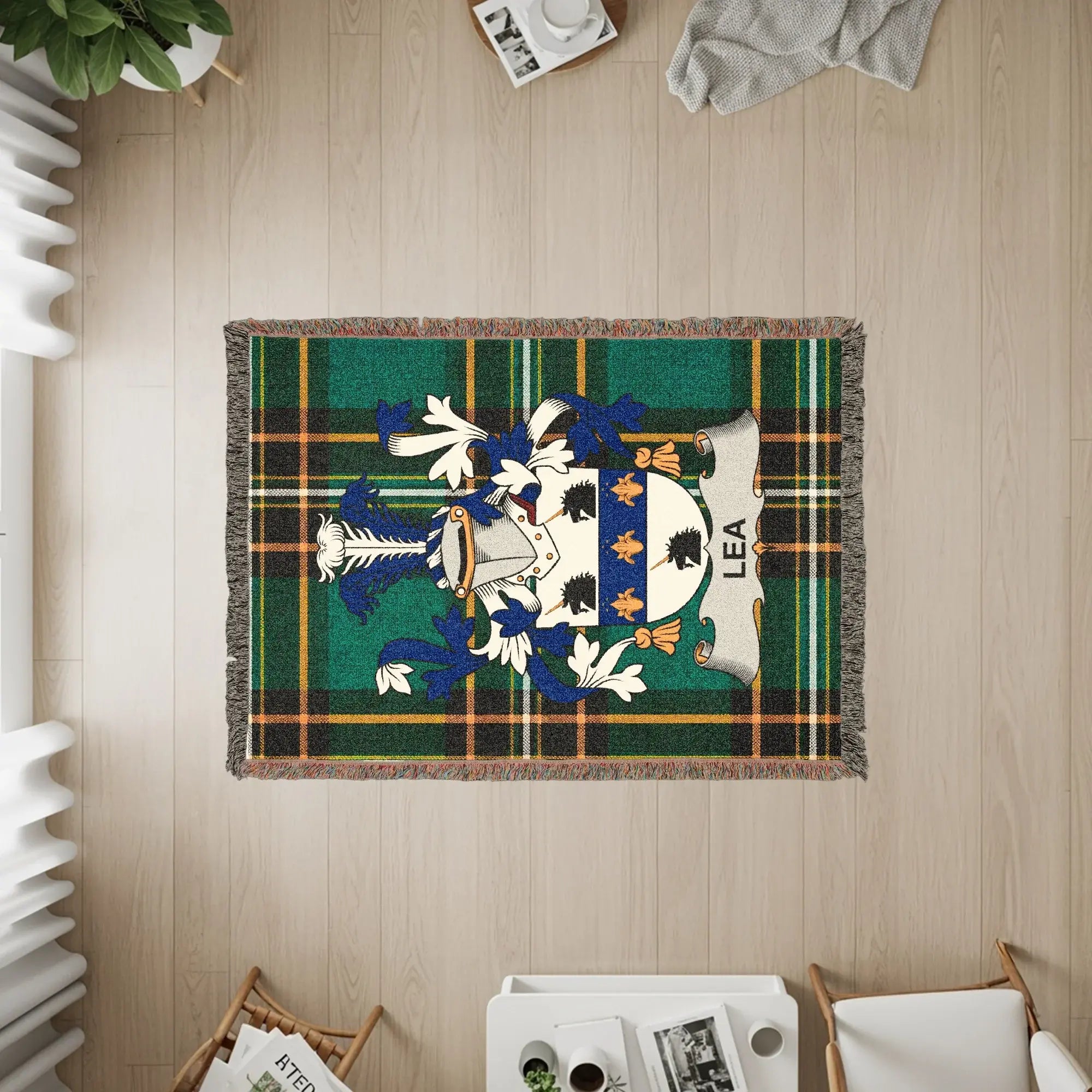 Woven throw blanket with green, blue, and gold plaid and a heraldic crest with the name LEA.