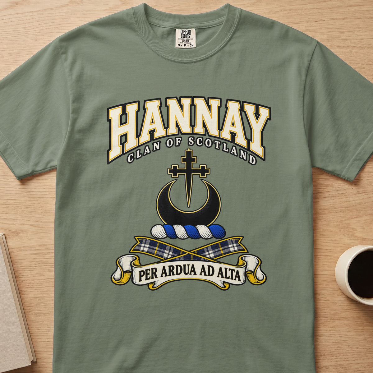 Hannay outlined cross and crescent crest graphic on a sage green Comfort Colors T-shirt, front view