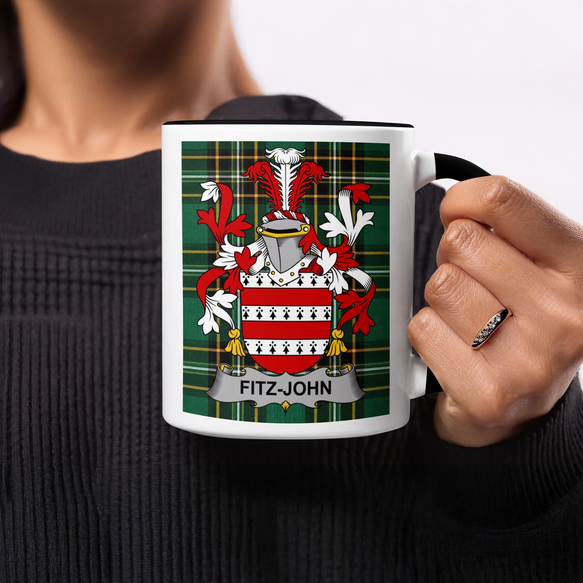 Fitz-John crest on a white mug with black handle, held by a person.