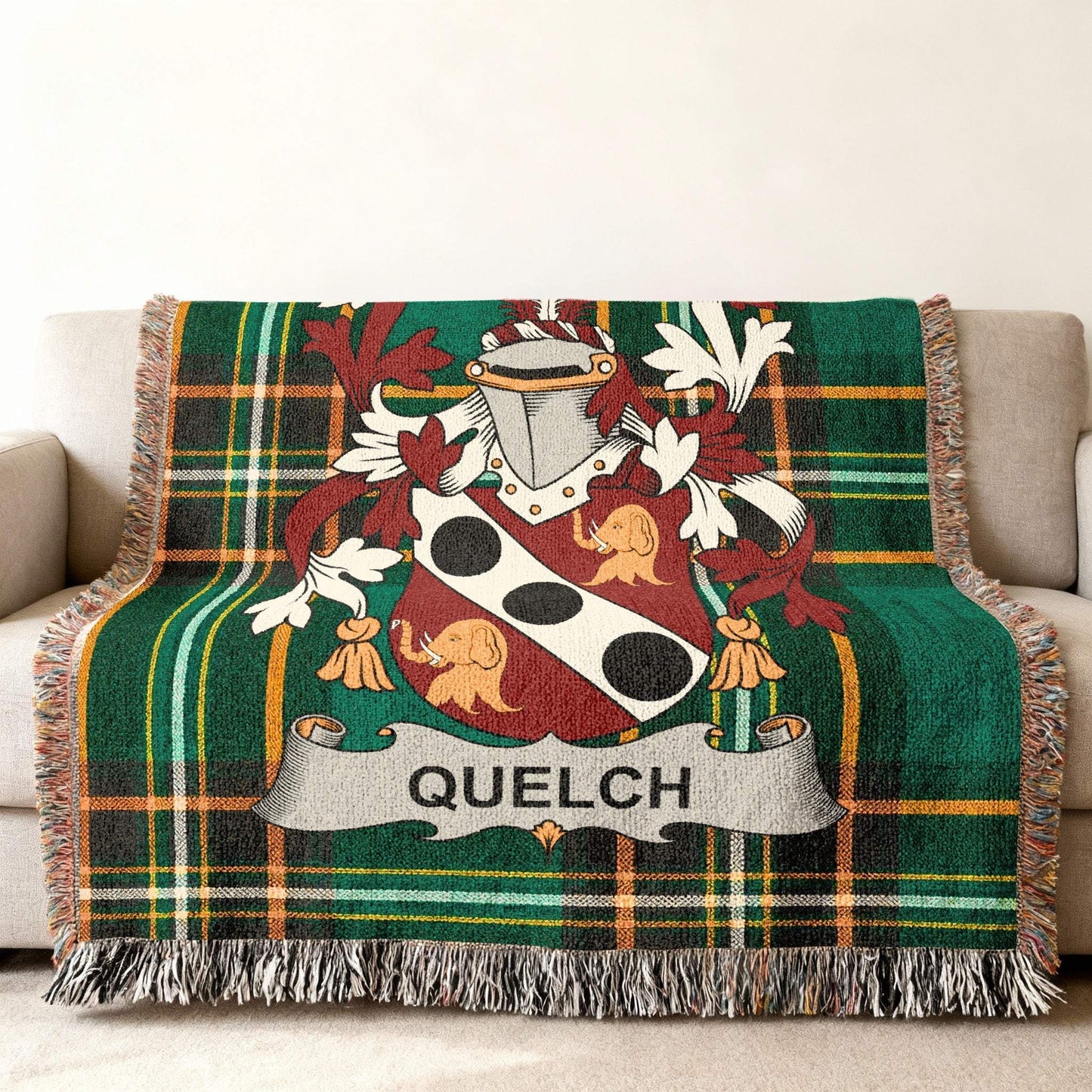 Green plaid throw blanket with a coat of arms and the name QUELCH.